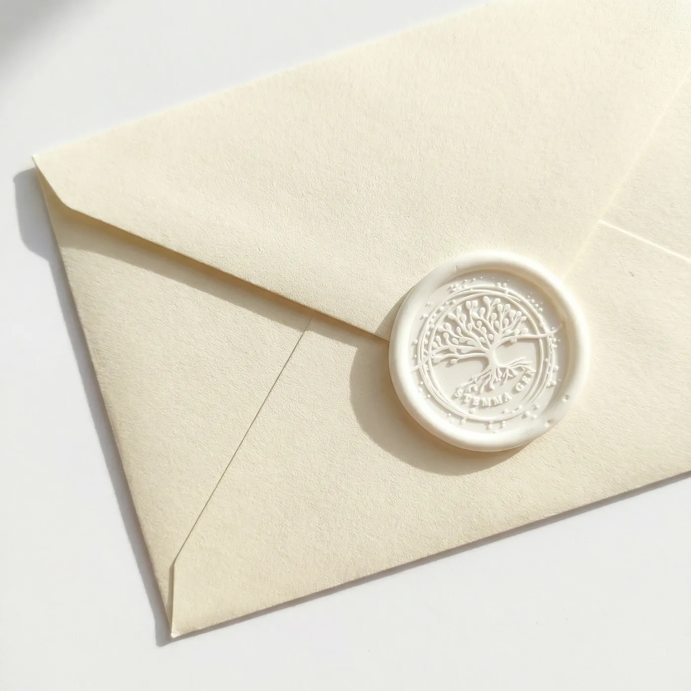 Enveloppe crème scellée d'un cachet de cire blanc représentant un arbre de vie